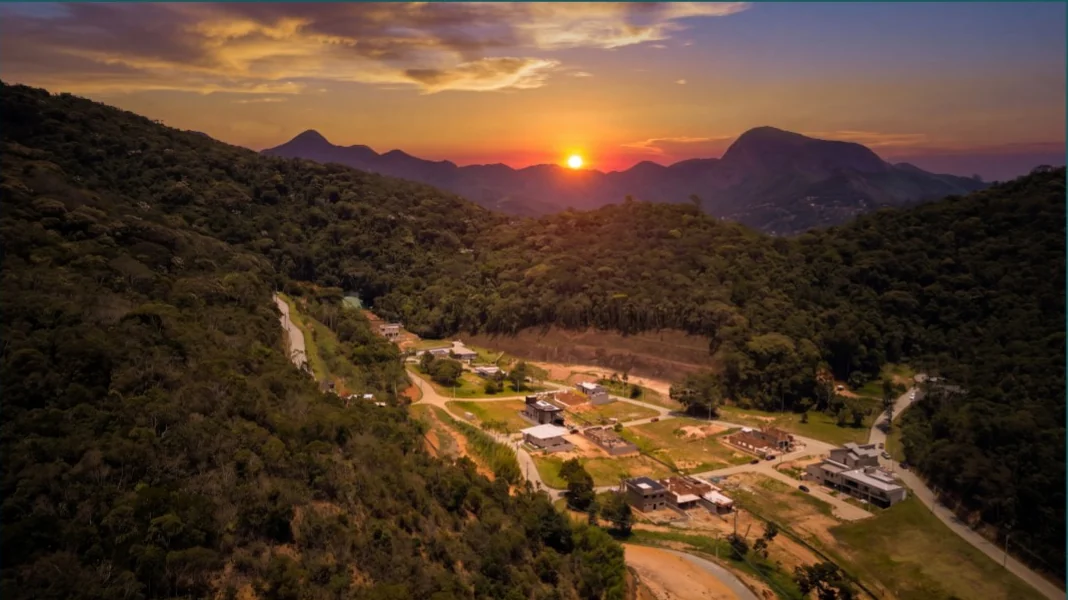 Vista aérea do Vale dos Pássaros ao pôr do sol, com as montanhas de Teresópolis ao fundo